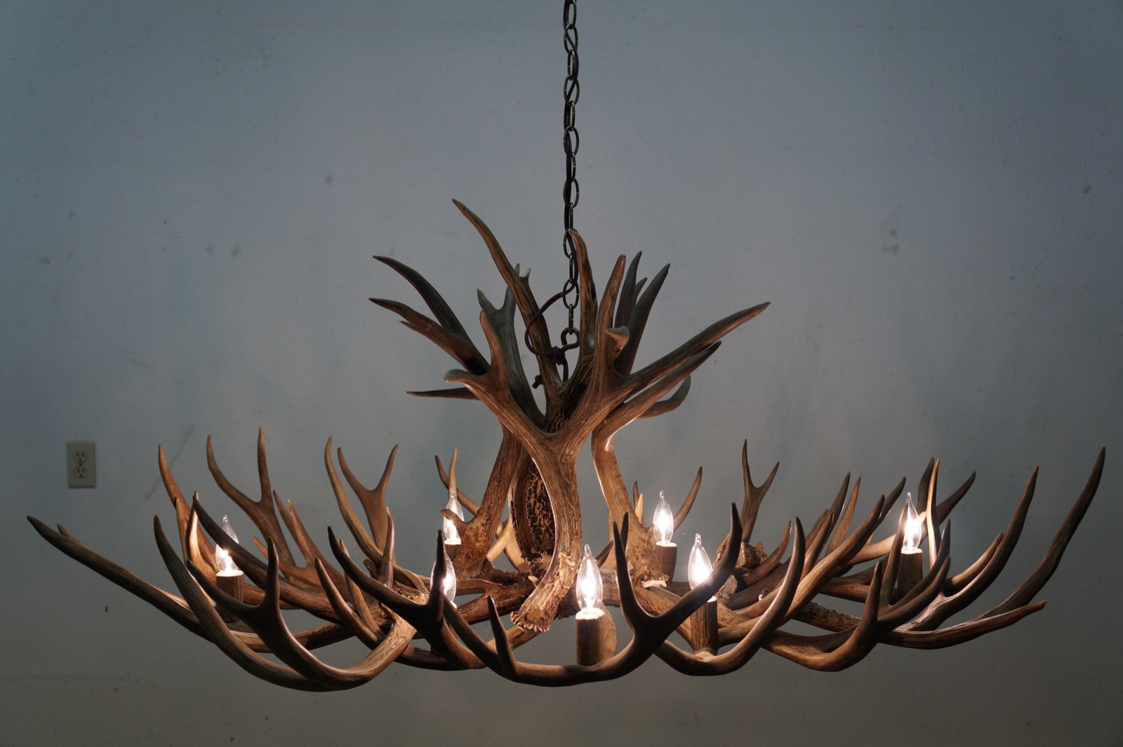 Twelve-light natural elk antler chandelier against a dark backdrop